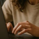 Uma pessoa concentrada usando seu laptop em um ambiente interno iluminado de forma suave e natural, transmitindo seriedade e contexto institucional
