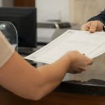 Pessoa recebendo uma certidão no balcão de um cartório, em um atendimento profissional e cordial, com ambiente interno realista, iluminação suave e aparência institucional.