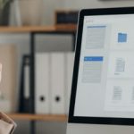 Pessoa em um escritório moderno organizando arquivos digitais no computador, com interface visual de pastas e documentos, iluminação natural e ambiente profissional.