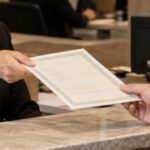 Funcionária de cartório entregando uma certidão a um cliente em um balcão de atendimento, em ambiente moderno e profissional, com iluminação suave e expressão cordial